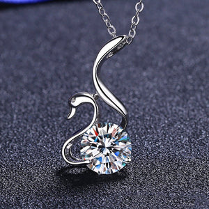 Silver swan-shaped necklace with a clear gemstone on a dark textured background