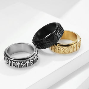 Three rings in black, silver, and gold on a white surface
