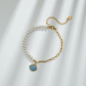 A gold-plated, sterling silver half chain bracelet with a seashell-shaped pendant and pearl beads.