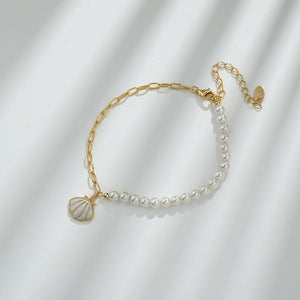 Gold bracelet with pearl beads on a white fabric background