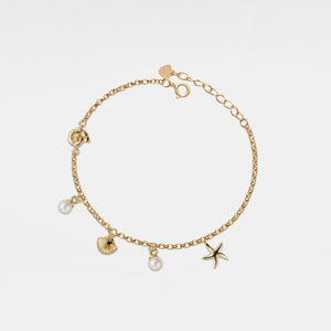 Gold bracelet with seashell, starfish and pearl charms on a light gray background