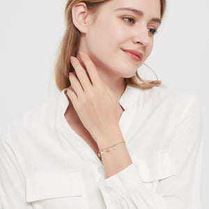 Model wearing a bracelet with seashell, starfish and pearl charms on a light gray background