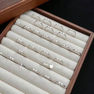 Wooden jewelry box with multiple silver rings on a white fabric lining