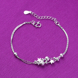 Silver bracelet with star and bead details on a purple background