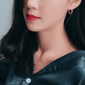 A model wearing small hoop earrings with gold plating, displayed against a white background.