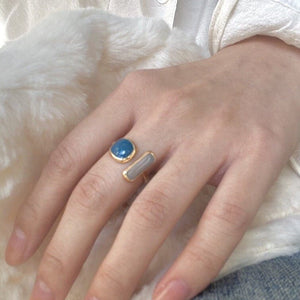 Model wearing a gold ring with blue and white stones