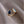 An open statement cocktail ring with gold plating, featuring a blue stone on one side and a white stone on the other, placed on a silky beige fabric.