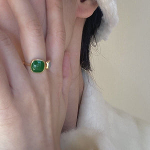 Model wearing a gold ring with green and white stones