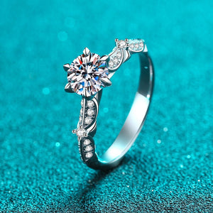 Silver ring with a large diamond and smaller stones on a teal background
