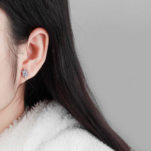 Woman wearing sea turtle-shaped earrings with gemstones on a white background