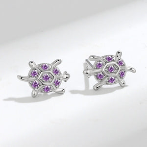A pair of small purple sea turtle stud earrings made of sterling silver with hypoallergenic finish.