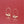 Gold hoop earrings with small decorative elements on a red background