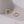 Gold hoop earrings with colorful gemstones on a gray surface