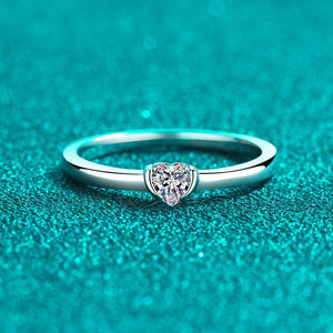 Silver ring with a heart-shaped diamond on a teal background