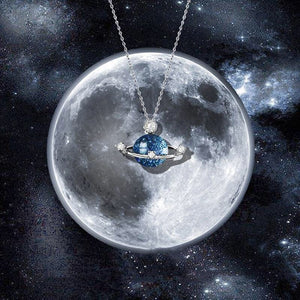 A sterling silver necklace with a blue glass pendant featuring a spaceman and a planet, set against a starry background.