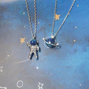 Two space-themed necklaces on a celestial background with stars and planets.