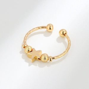 Gold spinner ring with star and round beads on a white background