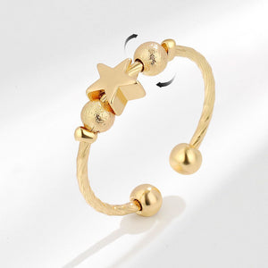 Gold spinner ring with star and round beads on a white background