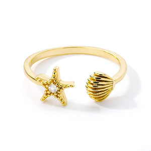Gold ring with starfish and shell designs on a white background.