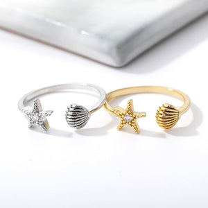 Two rings, one silver and one gold, with starfish and shell designs on a white background.