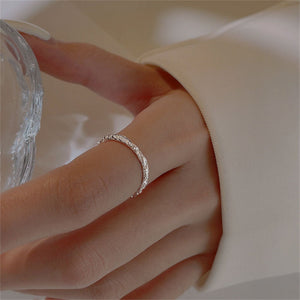 Close-up of a hand wearing a silver ring with a blurred background