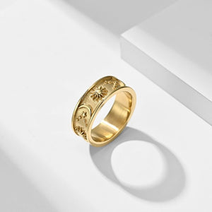 Gold celestial engraved ring with sun, moon, and stars design on a wide band