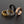 Four rings in gold, silver, black, and rose gold on a dark background