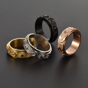 Four rings in gold, silver, black, and rose gold on a dark background