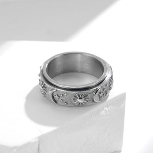 Silver celestial spinner ring with engraved sun, moon, and star details on a textured band