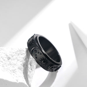 Black celestial spinner ring with engraved sun, moon, and star details on a textured band