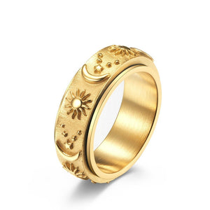 Gold celestial spinner ring with engraved sun, moon, and star details on a textured band