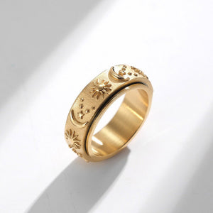Gold celestial spinner ring with engraved sun, moon, and star details on a textured band