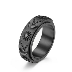 Black celestial spinner ring with engraved sun, moon, and star details on a textured band