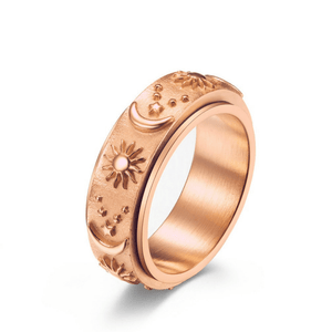 Rose gold celestial spinner ring with engraved sun, moon, and star details on a textured band