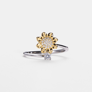Gold sunflower-shaped ring with diamond accents on a light gray background