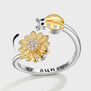 Silver ring with gold sunflower and ladybug charm on a white background
