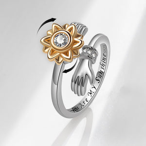 Two interlocking rings, one gold and one silver, on a light gray background.