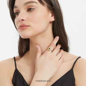 A model wearing a gold sunflower-shaped ring with a central projection gemstone on a white background