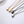 Set of four necklaces with teardrop-shaped pendants in rose gold, yellow gold, black, and silver on a white background.