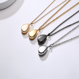 Set of four necklaces with teardrop-shaped pendants in rose gold, yellow gold, black, and silver on a white background.