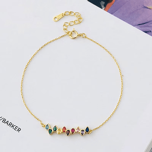 Sterling silver bracelet with gold plating and multicolored gemstone accents, displayed on an open book.