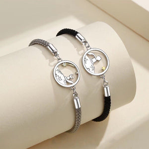 Two silver bracelets with circular charms on a beige surface