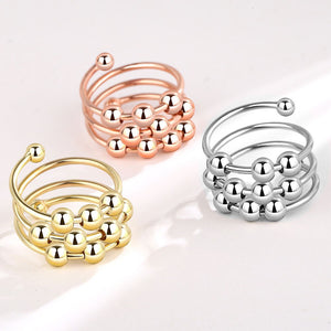 Three metallic rings in gold, rose gold, and silver on a light background