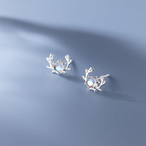 Silver earrings with a central gemstone on a blue background