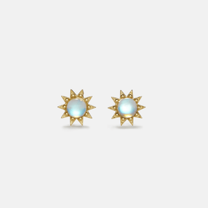 Pair of gold sun-shaped earrings with light blue gemstones on a light gray background