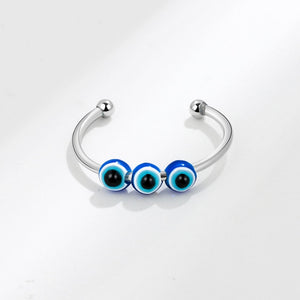 Silver spinner ring with blue and black evil eye beads on a white background