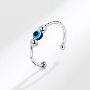 Silver spinner ring with blue and black evil eye beads on a white background