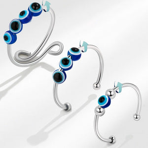 Three spinner rings with blue and black evil eye beads on a white background