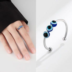 Woman wearing a spinner ring with blue and black evil eye beads on a white background