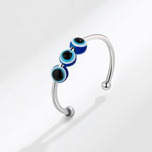 Silver spinner ring with blue and black evil eye beads on a white background